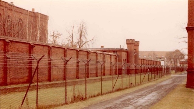 Участок тюремной стены с прополочным ограждением под высоким напряжением