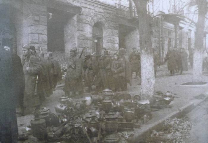 Советские солдаты идут по улице Киева. На тротуаре горы награбленных вещей, их не успели вывезти немцы. 6 ноября 1943 г. 