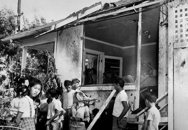 Люди осматривают повреждения дома после авианалета. 7 декабря 1941 г.