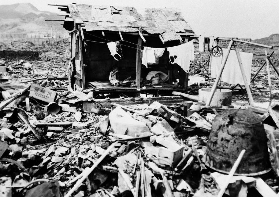 Японская семья ест рис в шалаше, построенном из обломков, оставшихся на том месте, где когда-то находился их дом в Нагасаки. 14 сентября 1945 г.