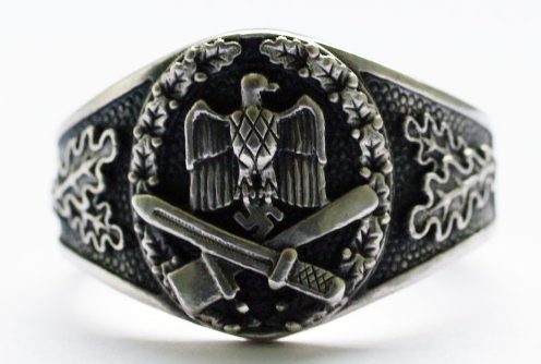 Наградной перстень выполнен из серебра 835-ой пробы с чернением. За основу дизайна щитка взят нагрудный знака Вермахта «За штурмовую атаку». По обоим бокам от щитка, кольцо украшено рельефным растительным орнаментом.