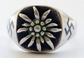 Перстень из серебра 835-ой пробы с рельефным изображением эдельвейса. С обеих сторон щитка вытравлена свастика. Поле щитка зачернено.