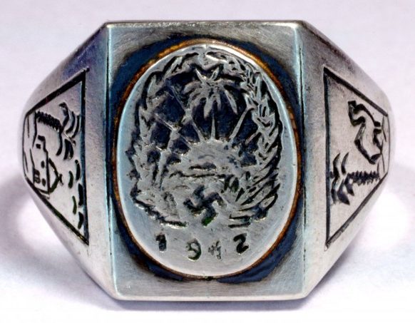 Памятный перстень «Немецкий Африканский Корпус 1942» изготовленный из серебра 835-ой пробы. На щитке изображена эмблема корпуса – свастика на фоне пальмы и восходящего солнца. По обеих сторонах щитка изображена пальма.