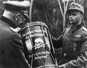 Гельмут Беккер принимает барабан с надписью «От молодых товарищей из Вартеланда танковой дивизии «Мертвая Голова». 1944 г.