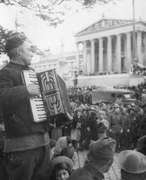 Красноармеец играет на аккордеоне у здания парламента. Май 1945 г.