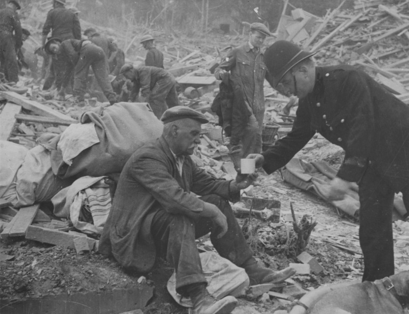 Полицейский дает чашку чая мужчине, оставшемуся без крова после падения на его дом немецкой ракеты ФАУ-1. 1944 г. 