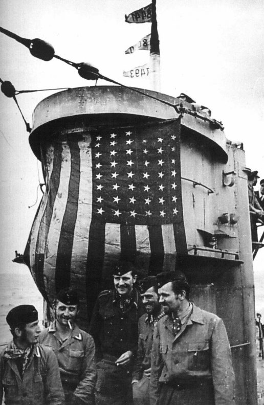 Подводники у захваченного флага с американского судна, растянутого на рубке. 1942 г.