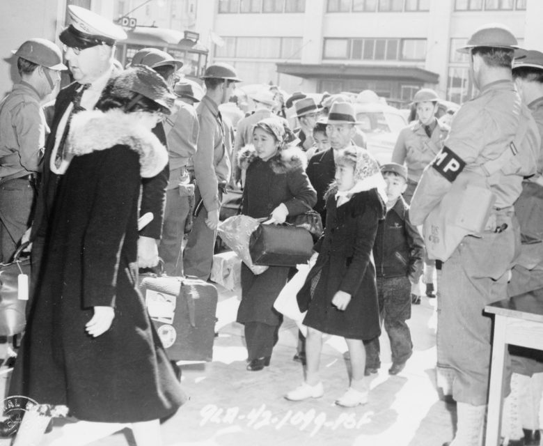 Японская семья на вокзале Сан-Франциско в конвое военной полиции во время депортации в лагерь. Апрель 1942 г.