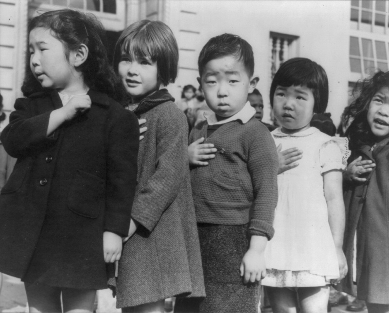 Японские и американские дети на церемонии подъема флага в школе Вэйлл в Сан-Франциско. Большинство из японских детей на этих фотографиях были депортированы в лагеря для интернированных вскоре после того, как эти фото были сделаны. Апрель 1942 г.