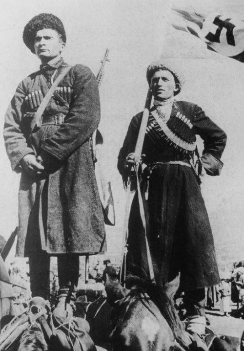 Казаки-хиви позируют с флагом, стоя на спинах лошадей. 1943 г.