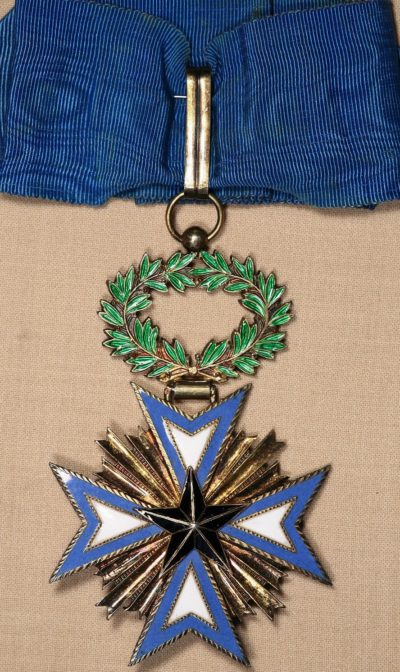 Аверс и реверс золотого знака Командора ордена Чёрной звезды на шейной ленте.