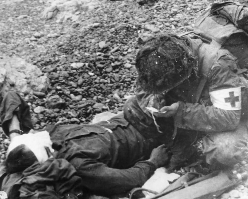 Медик 4-й американской пехотной дивизии оказывает помощь раненому солдату на Омаха-Бич. 6 июня 1944 г.