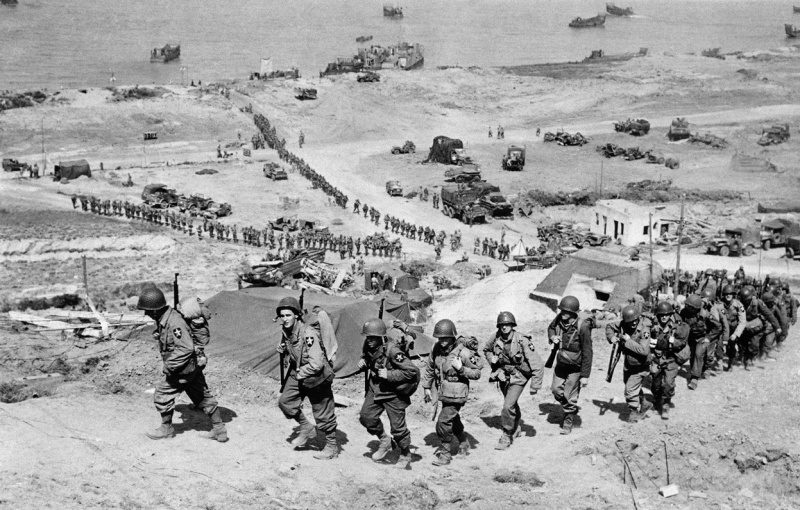Американские солдаты поднимаются по склону на побережье Омаха. 6 июня 1944 г.