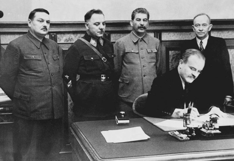 В. М. Молотов подписывает договор между СССР и Териокским правительством. Стоят: А.А. Жданов, К.Е. Ворошилов, И.В. Сталин, О.В. Куусинен. 2 декабря 1939 г.
