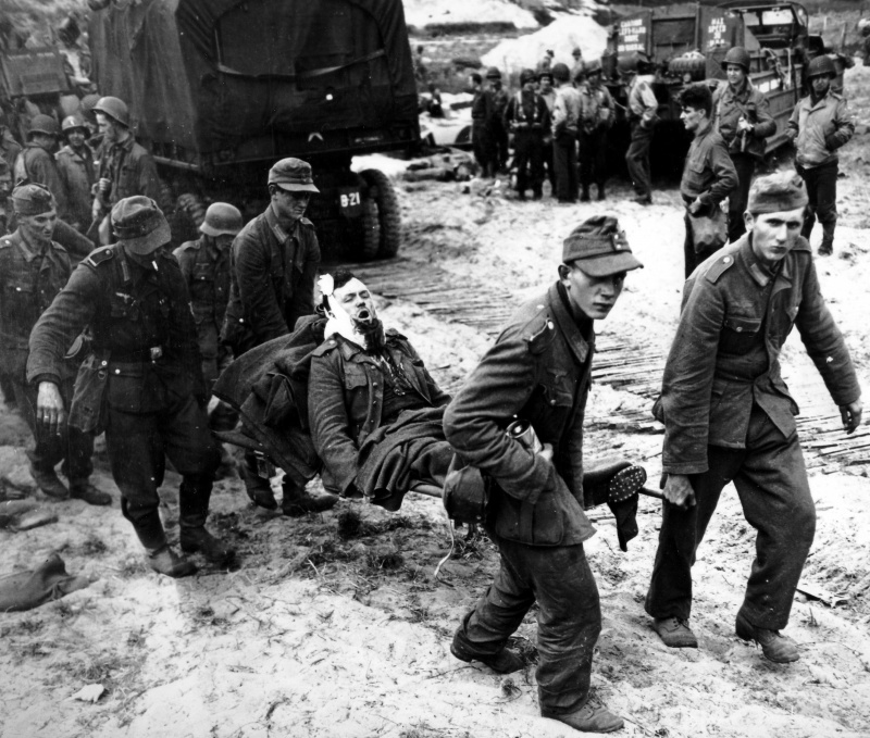Немецкие военнопленные несут своих раненых в американский полевой госпиталь. Пляж Сен-Лоран-сюр-Мер. Июнь 1944 г.