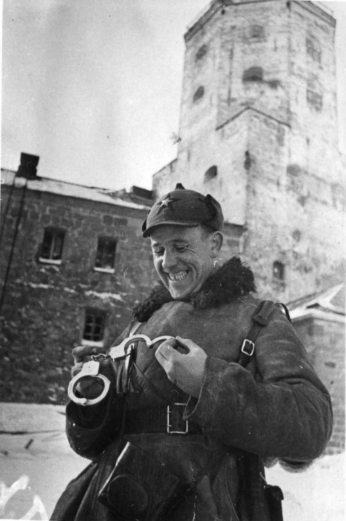 Советский офицер рассматривает финские наручники, найденные в Выборгском замке. Февраль 1940 г.