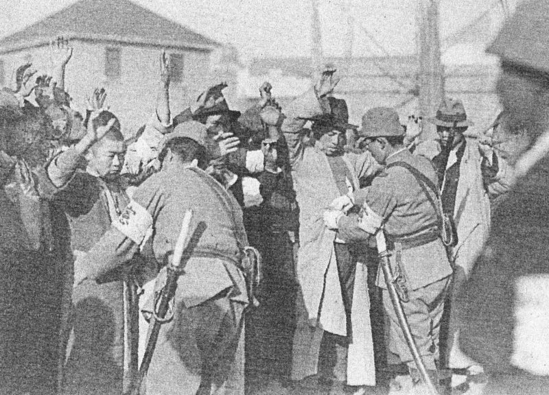 Японские солдаты обыскивают горожан.