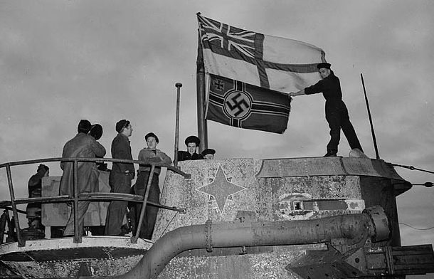 Канадские моряки поднимают флаг британских ВМС над захваченной немецкой подводной лодкой в Сент-Джонс. 1945 г. 