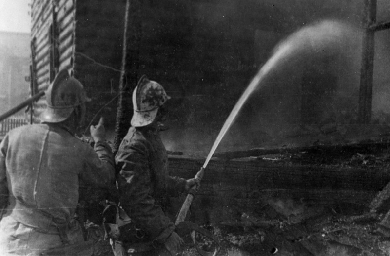 Пожарные тушат горящий дом после авианалета. Июнь 1943 г. 