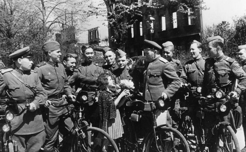 Немецкая девочка дарит цветы советским военнослужащим. Июнь 1945 г. 