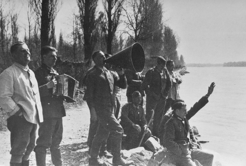 Немецкие солдаты под музыку баяна ведут диалог с французами на берегу Рейна. Март 1940 г.