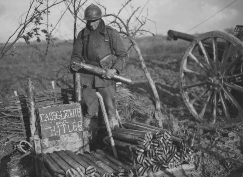 Французский артиллерист у 75-мм легкой полевой пушки на Западном фронте. Надпись на ящике «Casse-Croute pour Hitler» переводится как «Закуска для Гитлера». Октябрь 1939 г.