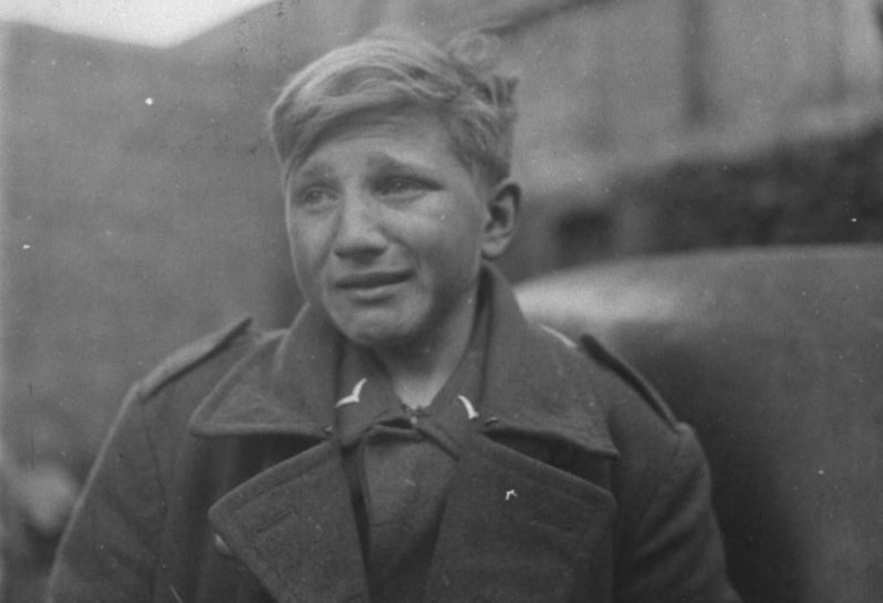Пятнадцатилетний немецкий зенитчик Ганс-Георг Хенке, взятый в плен солдатами США в городе Рехтенбах. Германия. Март 1945 г. 