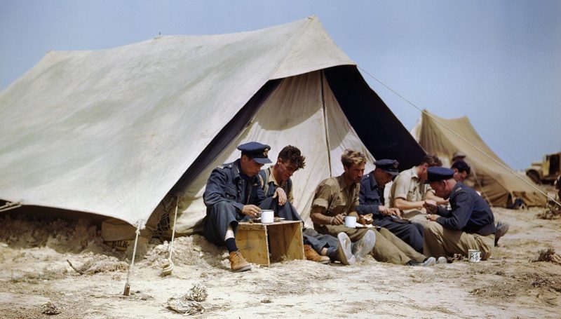 Пилоты истребителей Spitfire ВВС Канады обедают возле палатки в Губрине. Апрель 1943 г.