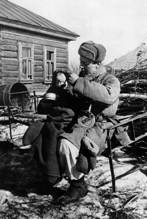 Старший сержант Моисеев кормит сироту в освобожденной деревне Извеково. Март 1943 г. 
