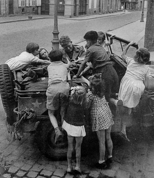 Американский солдат раздает шоколад детям в Динаре. Франция,1944 г.