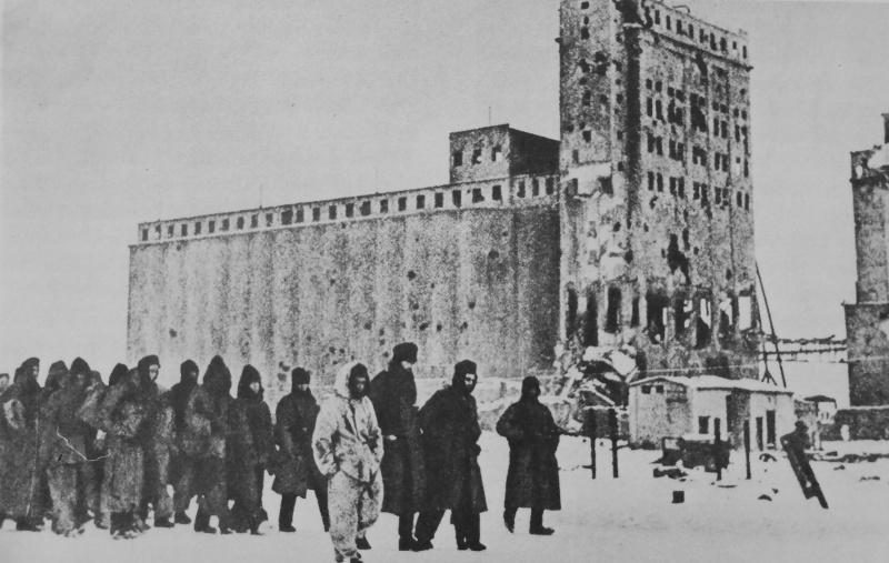 Красноармеец конвоирует колонну немецких военнопленных у здания элеватора в Сталинграде. 1943 г.