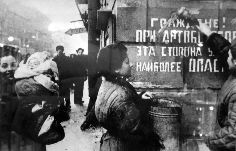 Ленинградцы закрашивают надпись «Граждане! При артобстреле эта сторона улицы наиболее опасна». Январь 1944 г.