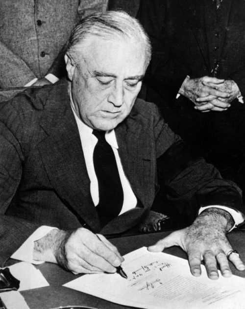 Президент США Франклин Рузвельт подписывает декларацию об объявлении войны Японии.