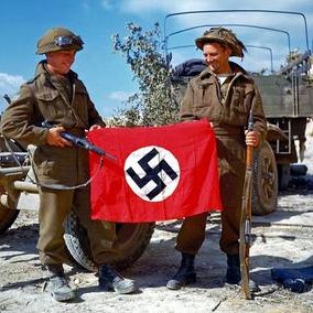 Канадские солдаты с нацистским флагом захваченным в битве к юго-востоку от Кана. 10 августа 1944 г.