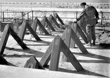 Канадский солдат осматривает противотанковые препятствия на пляже в Бланкенберге. Бельгия, 11 сентября 1944 г.