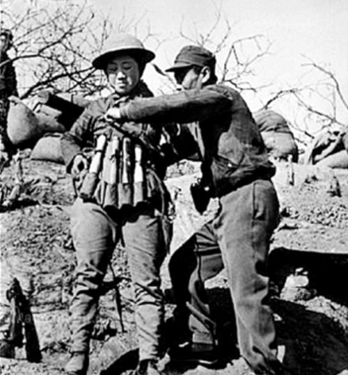 Китайский террорист-смертник надевает взрывной жилет, изготовленный из ручных гранат, для использования при нападении на японские танки в битве при Тайержуане. 1938 г.