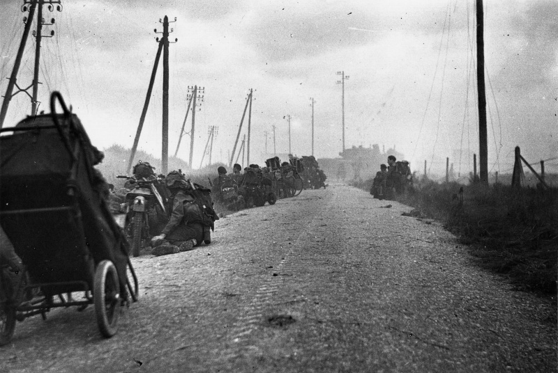 Канадские солдаты укрываются от огня на дороге у пляжа Юнона. 6 июня 1944 г.