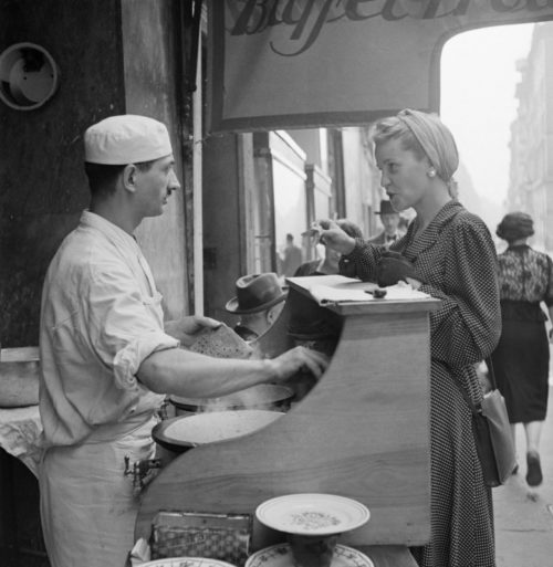 Парижанка завтракает в блинной на улице города. Май 1941 г.