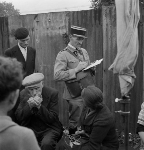 Полицейский выписывает штраф продавцу на блошином рынке в оккупированном Париже. Май 1941 г.