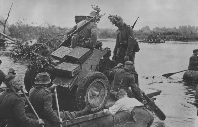 Немецкие артиллеристы переправляют противотанковую пушку на лодке через Маас. Май 1940 г.