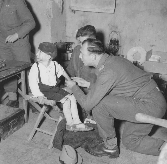 Британский медик оказывает помощь итальянскому мальчику, пострадавшему в результате немецкого артобстрела. Январь 1944 г. 