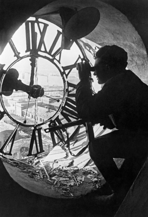 Красноармеец ведет наблюдение через циферблат ратушных часов во время боев в Будапеште. Январь 1945 г.