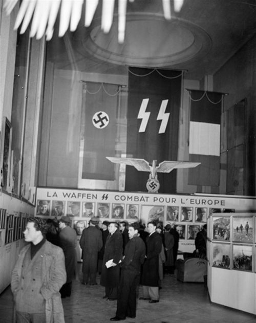 Посетители фотовыставки «Войска СС» в выставочном зале фирмы «Ситроен» в Париже. Февраль 1944 г.