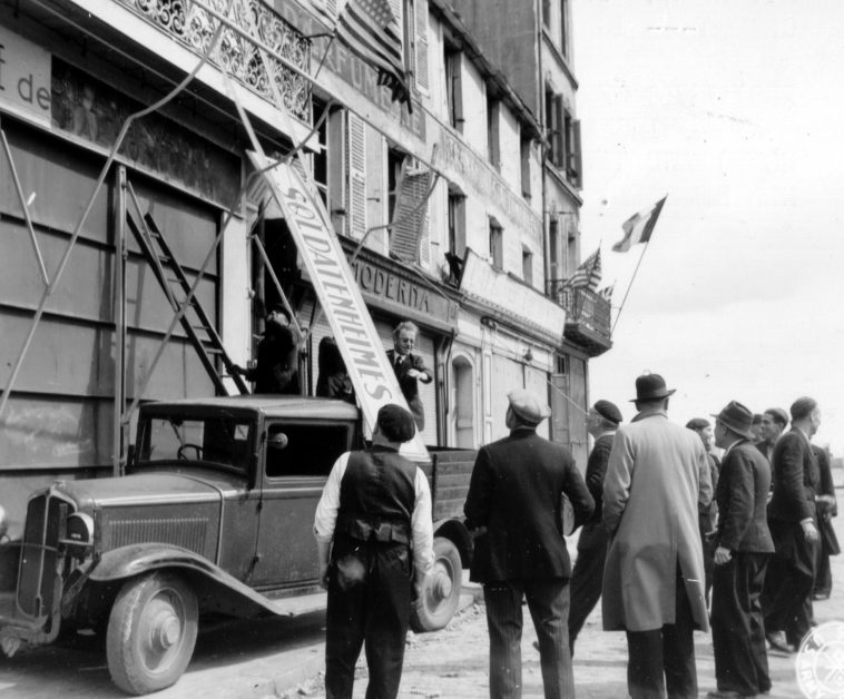Французы снимают немецкую вывеску с фасада здания в Шербуре. 28 июня 1944 г. 