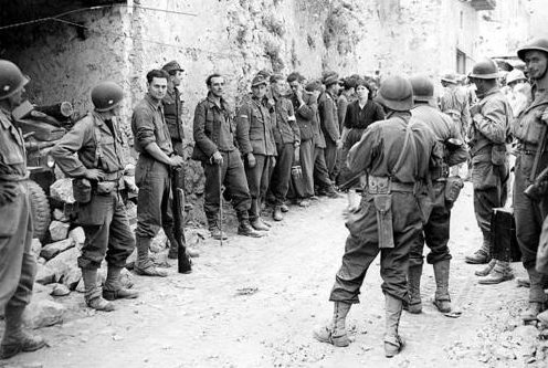 Солдаты французского экспедиционного корпуса охраняют немецких военнопленных на улице итальянского городка. Июль 1944 г. 