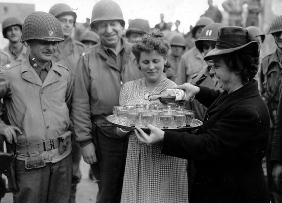 Француженки угощают американских офицеров вином на площади в Тревьере. 14 июля 1944 г. 