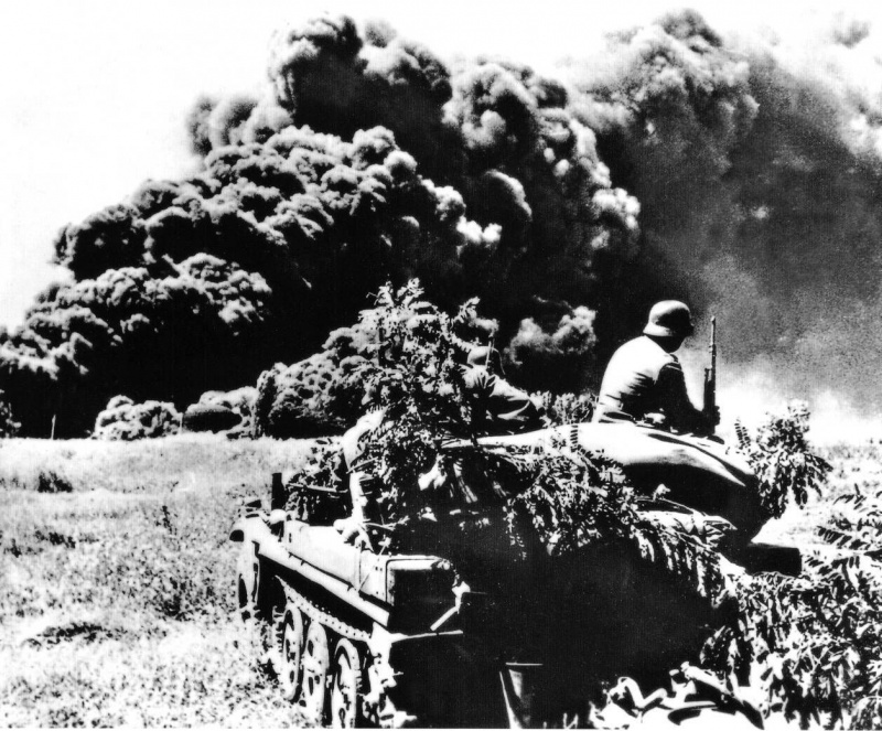 Немецкие солдаты на фоне дыма от горящих нефтяных скважин Майкопа, подожженных при отступлении советских войск. Август 1942 г. 