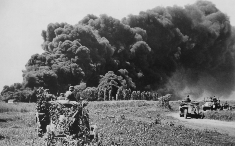 Немецкие солдаты на фоне дыма от горящих нефтяных скважин Майкопа, подожженных при отступлении советских войск. Август 1942 г. 