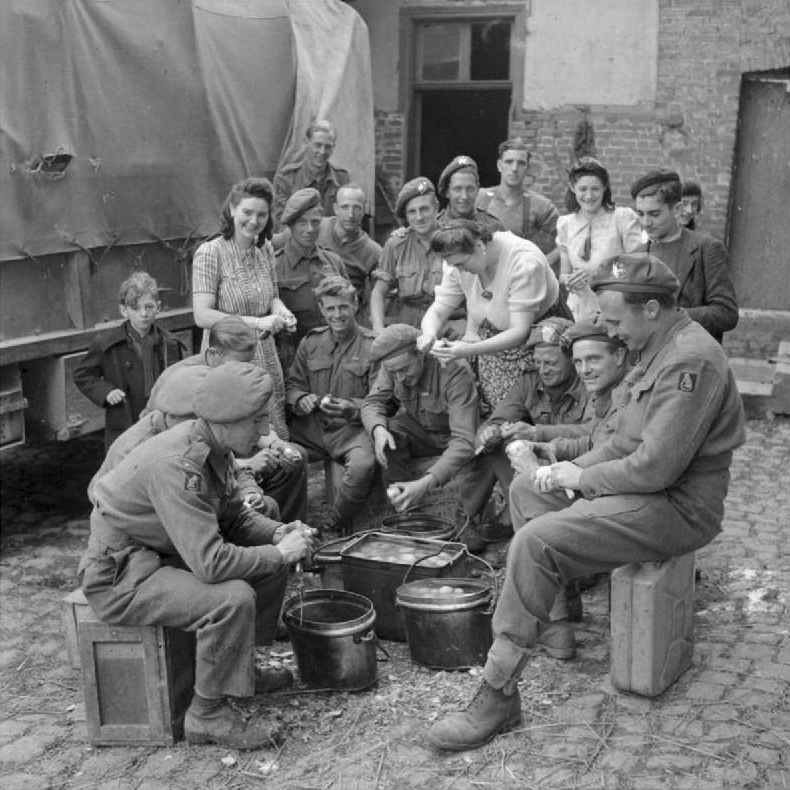 Французские женщины помогают британцам чистить картошку возле Сен-Поль. 3 сентября 1944 г.