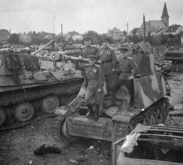 Группа офицеров 359-й стрелковой дивизии на фоне трофейной немецкой бронетехники. Май 1945 г.